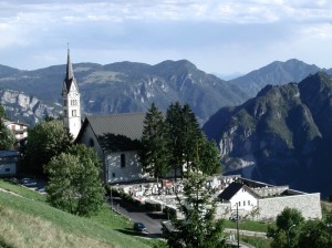 Chiesa S.Antonio, campanile, cimitero in Luserna. Sullo sfondo Altipiano di Asiago, Valdastico, in lontananza Colli Euganei.