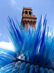 Piazza con  scultura di murano e torre sullo sfondo