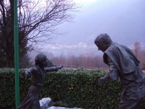 monumento all’emigrante e sfondo su revine lago